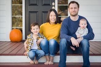 Young mixed-race chinese and caucasian family portrait on their front porch