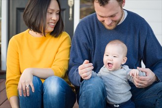 Young mixed-race chinese and caucasian family portrait on their front porch