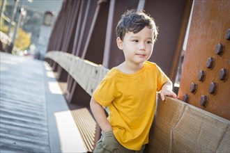 Handsome mixed-race boy leaning on bridge outdoors