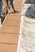 Construction worker using trowel on wet cement forming coping around new pool