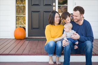 Young mixed-race chinese and caucasian family portrait on their front porch