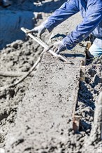 Pool construction worker working with A smoother rod on wet concrete