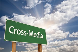 Cross-Media green road sign with dramatic clouds and sky