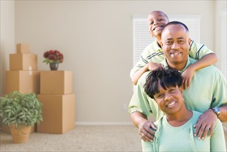 Happy african american family in room with packed moving boxes