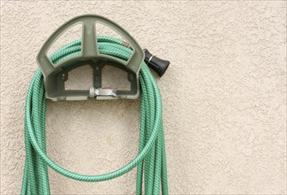 Garden hose hanging on stucco wall