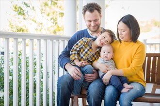 Young mixed-race chinese and caucasian family portrait on their front porch