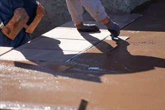 Construction worker smoothing wet cement with hand edger tool