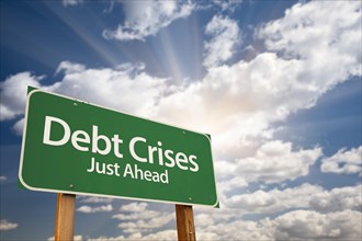 Debt crises green road sign against dramatic sky