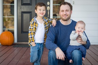 Young mixed-race father and sons on front porch