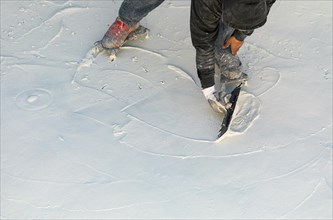 Worker wearing spiked shoes smoothing wet pool plaster with trowel