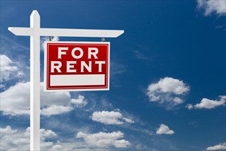 Right facing for rent real estate sign over blue sky and clouds with room for your text