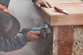 Construction worker using grinder at construction site