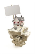 Small house on stacks of hundred dollar bills and blank sign isolated on a white background