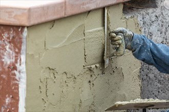 Tile worker applying cement with trowel at pool construction site