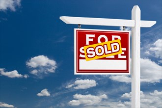 Left facing sold for sale real estate sign over blue sky and clouds with room for your text