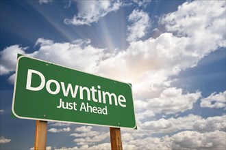 Downtime just ahead green road sign with dramatic clouds and sky