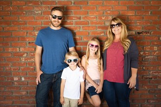 Young caucasian family wearing sunglasses against brick wall