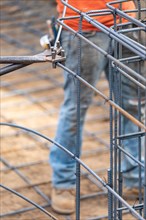 Worker using tools to bend steel rebar at construction site