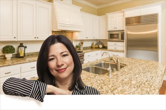 Hispanic woman leaning against white board in custom kitchen interior