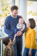 Young mixed-race chinese and caucasian family portrait on their front porch