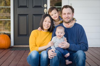 Young mixed-race chinese and caucasian family portrait on their front porch