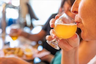 Female sipping glass of micro brew beer at bar with friends