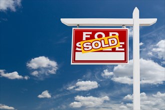 Left facing sold for sale real estate sign over blue sky and clouds with room for your text