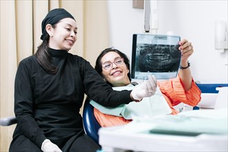 View of dentist with patient reviewing x-ray. Dentist showing x-ray to patient
