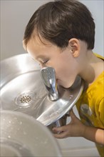 mixed-race boy drinking from the fresh water fountain