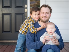 Young mixed-race father and sons on front porch