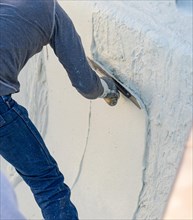 Worker smoothing wet pool plaster with trowel