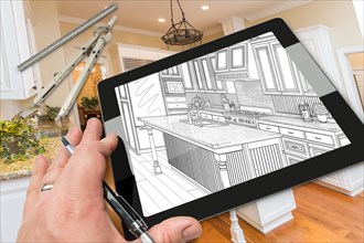 Hand of architect on computer tablet showing drawing of kitchen photo behind with compass and ruler