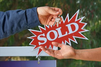 Handing over the keys with A sold real estate sign
