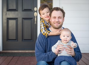 Young mixed-race father and sons on front porch