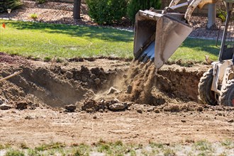 Small bulldozer digging in yard for pool installation