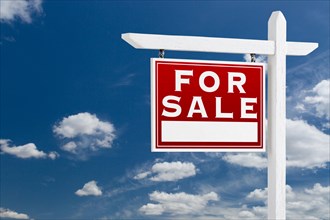 Left facing for sale real estate sign over blue sky and clouds with room for your text