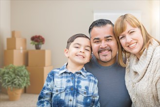 mixed-race family in empty room with moving boxes and plants