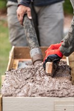 Construction workers pouring and leveling wet cement into wood framing