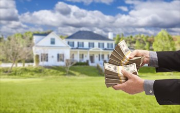 Man handing over thousands of dollars in front of beautiful house