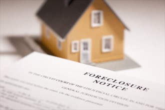 Foreclosure notice and model home on gradated background with selective focus