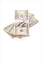 House keys on stack of money isolated on a white background