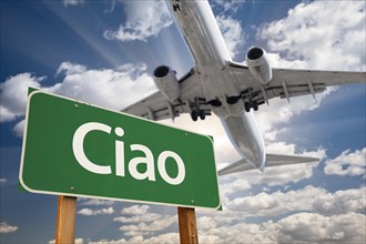 Ciao green road sign and airplane above with dramatic blue sky and clouds