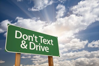 Don't text and drive green road sign with dramatic sky