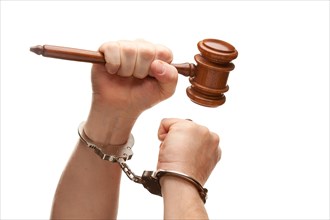 Handcuffed man holding wooden gavel in his fist isolated on a white background