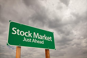 Stock market just ahead green road sign with dramatic storm clouds and sky