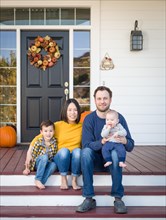 Young mixed-race chinese and caucasian family portrait on their front porch