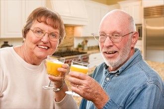 Happy senior couple with glasses of orange juice isolated on a white background