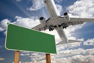 Blank green road sign and airplane above with dramatic blue sky and clouds