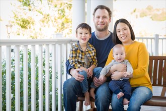 Young mixed-race chinese and caucasian family portrait on their front porch