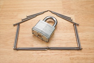 House of nails with lock on a wood background